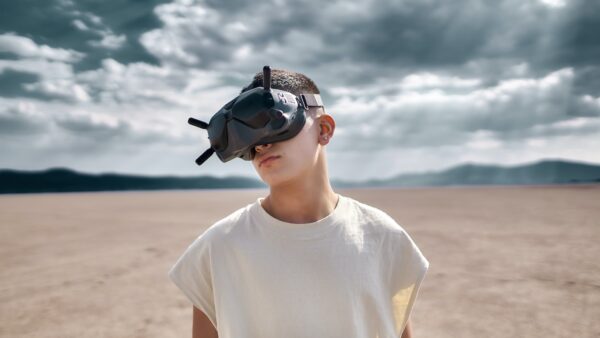 man in white crew neck t-shirt wearing black sunglasses standing on brown sand during daytime